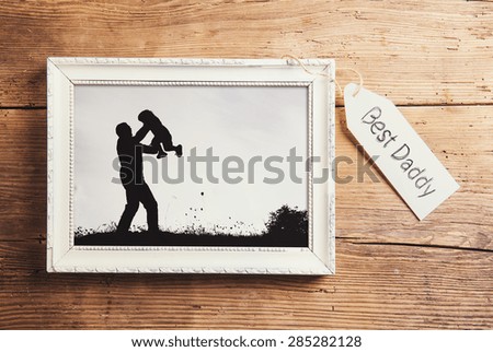 Fathers day composition - picture frame with a black and white photo. Studio shot on wooden background.