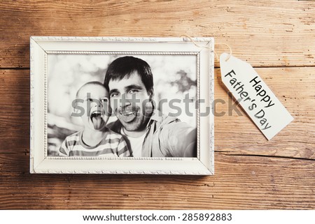 Fathers day composition - picture frame with a black and white photo. Studio shot on wooden background.