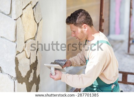 Mason putting decorative natural stones on a wall