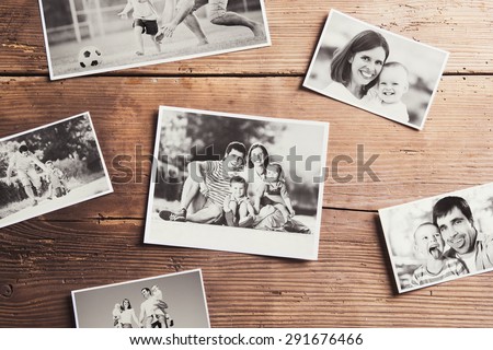 Black and white family photos laid on wooden table background.
