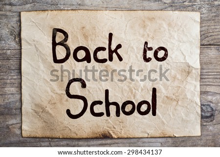 Piece of old rumpled paper with Back to school sign on wooden floor background