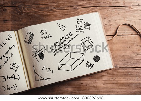 School book with mathematics doodles. Studio shot on wooden background.