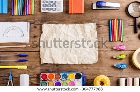 Desk with stationary and blank sheet of paper. Studio shot on wooden background.