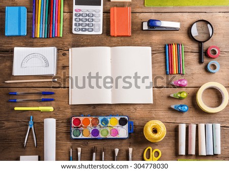 Desk with stationary and with blank notebook. Studio shot on wooden background.