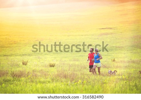 Active seniors running with their dog outside in green nature