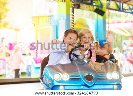 Senior couple having a ride in the bumper car at the fun fair
