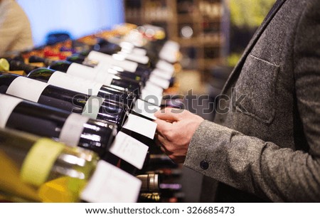 Unrecognizable young man in a wine shop choosing a wine