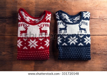 Two winter sweaters laid on a wooden table background