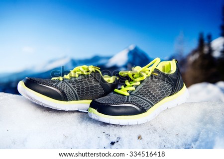 Gray running shoes laid outside on snow