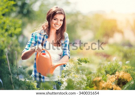 Beautiful young woman gardening outside in summer nature
