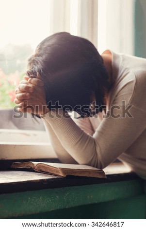 Unrecognizable woman reading her Bible and praying