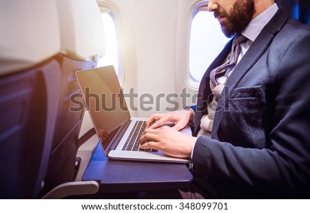 Unrecognizable young businessman with notebook sitting inside an airplane