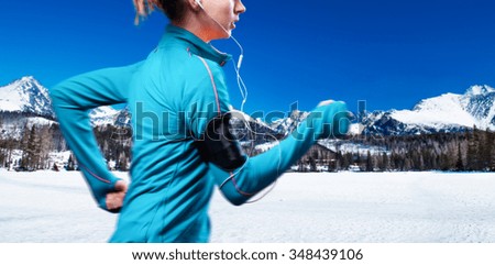 Young woman jogging outside in sunny winter mountains