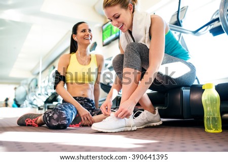 Two attractive fit women in gym preparing for workout
