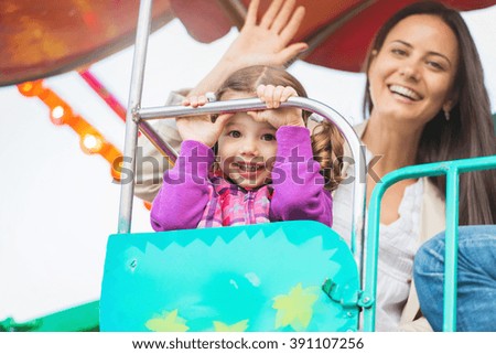 Mother and daughter enjoying fun fair ride, amusement park