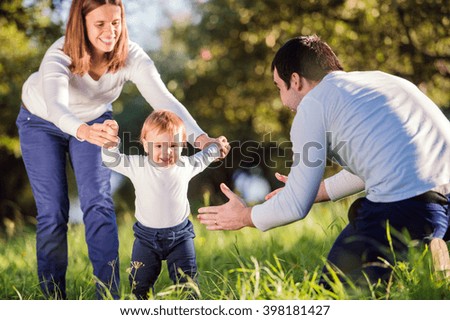 Parents holding their little son making first steps