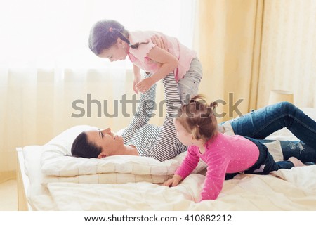 Mother having fun with her daughters in her bedroom