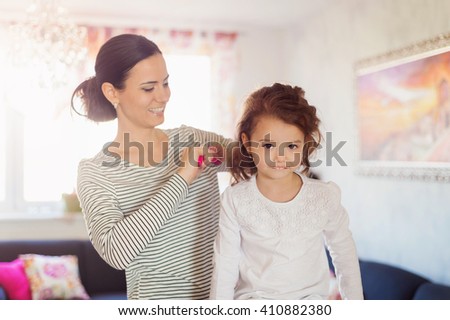 Mother combing hair of her daughter in the morning