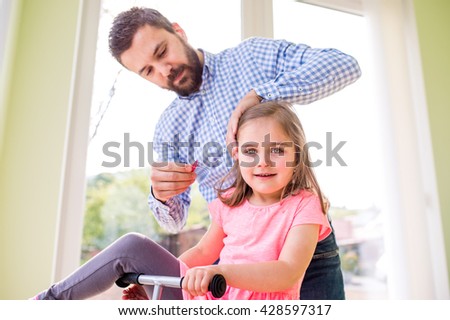 Father with daughter, styling her hair, riding bicycle indoors