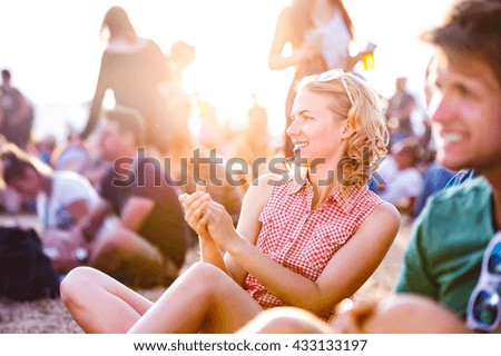 Teenagers at summer music festival, sitting on the ground