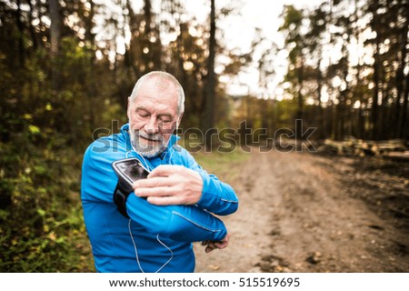 Senior runner in nature with smart phone and earphones.