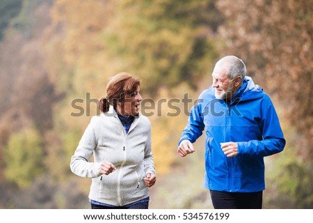 Beautiful senior couple running outside in sunny autumn nature