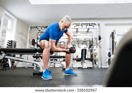 Senior man in sports clothing in gym working out with weights.