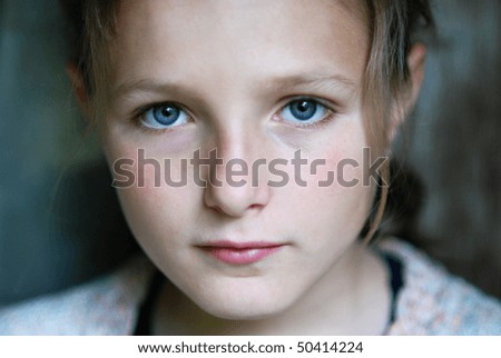 Sad little girl is looking with serious face at camera.