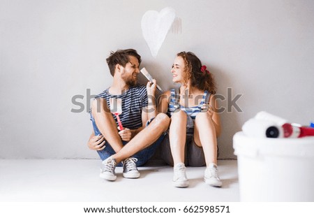 Young couple in love painting walls in their new home.