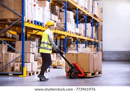 Woman warehouse worker with hand forklift truck.