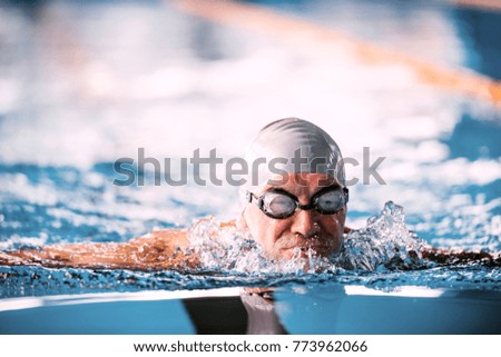 Senior man swimming in an indoor swimming pool.