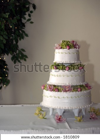 Wedding Cake with Flowers and Greens with Lighted Tree in Background