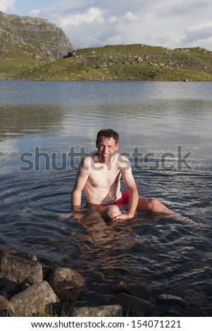 Man taking a cold bath in mountain lake Elversvatnet (Roldalsfjellet, Norway)
