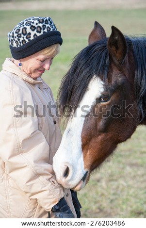 Senior woman sharing a close bond and trust with her beautiful horse.