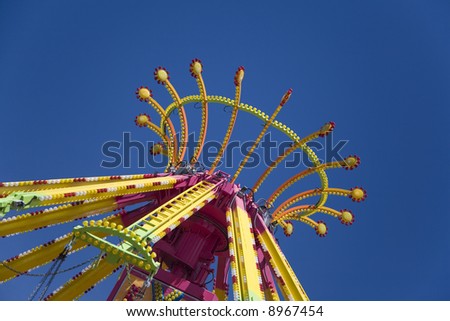 Top of spinning carnival ride against bold blue sky.  Suggests family fun at a summer carnival or fair.