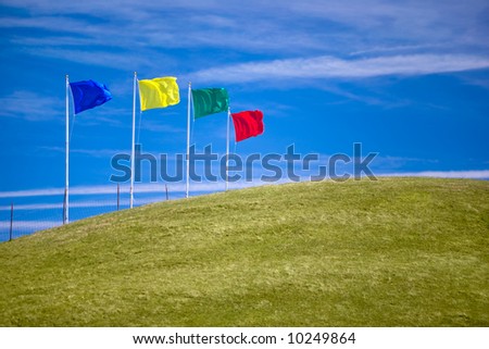 Four colorful flags on green grassy hill invite shoppers to attend an open house or other sales event.  Ample room for copy.