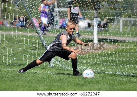 Young Soccer Goalie Tries to Stop Low Shot