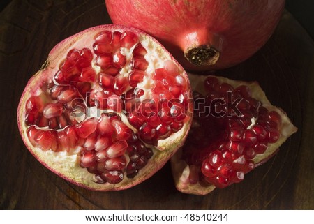 Pomegranate on wooden surface broken open with seeds scattered