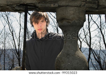 a young man in the old pavilion in the jacket looks seriously at the background of columns