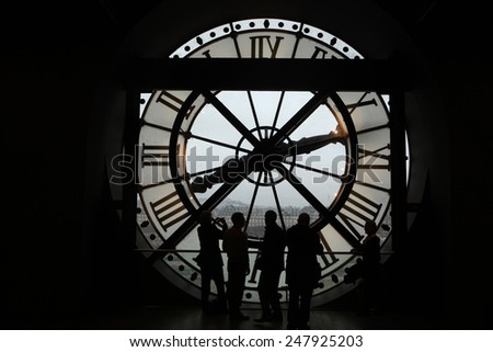 PARIS, FRANCE - JANUARY 8, 2013: Visitors observe a panoramic view thought the glass clock in the Musee d Orsay in Paris, France.