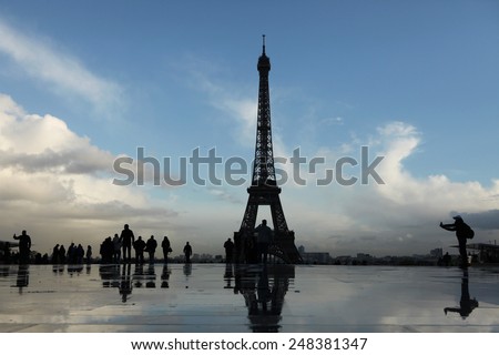 PARIS, FRANCE - NOVEMBER 14, 2013: People walk in front of the Eiffel Tower on the Champ de Mars in Paris, France.