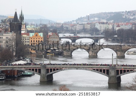 PRAGUE, CZECH REPUBLIC - APRIL 6, 2013: Athletes run over the Manes Bridge on the Vltava River during a marathon run in Prague, Czech Republic. The Charles Bridge is seen in the background.
