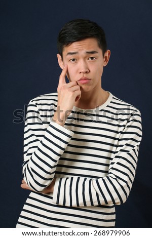 Pensive young Asian man looking at camera