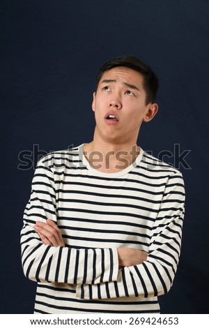 Disappointed young Asian man with crossed hands looking up