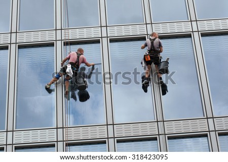 PRAGUE, CZECH REPUBLIC - SEPTEMBER 5, 2015: Two rope access workers clean windows in an office building in Charles Square in Prague, Czech Republic.
