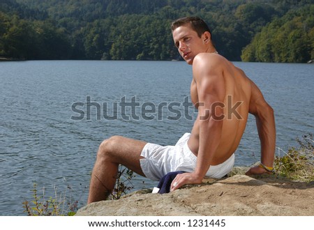 Muscular male model sitting at the beach