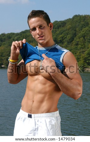 stock photo Muscular male model undressing at the beach