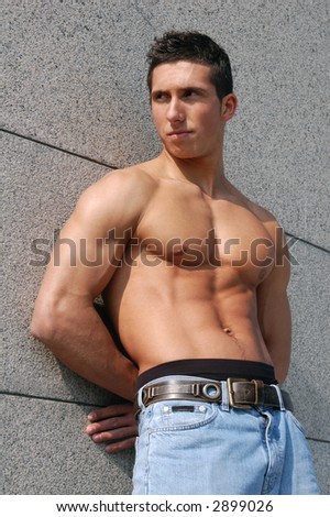 Shirtless muscular male model in front of the granite block wall