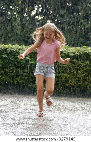 Young girl running in the heavy rain in the park
