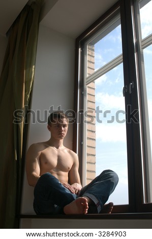 Sexy muscular man sitting on the window-sill